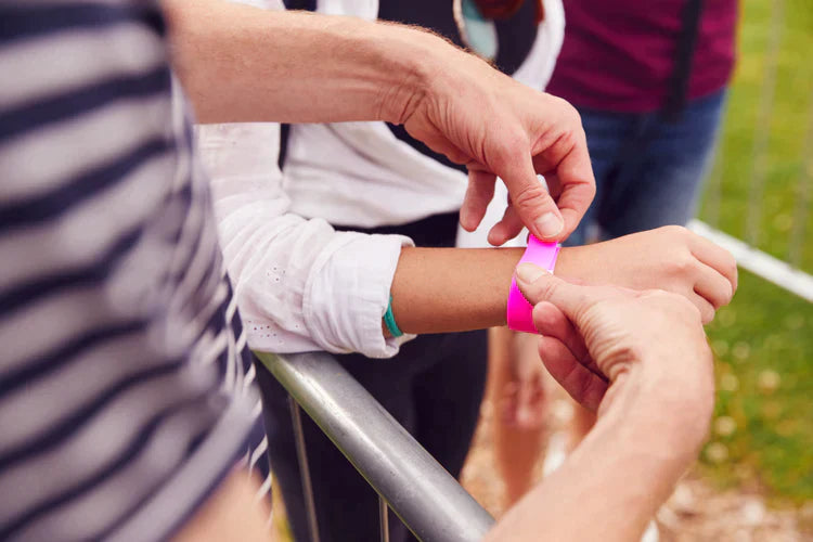 En person legger et rosa armbånd på noens håndledd.