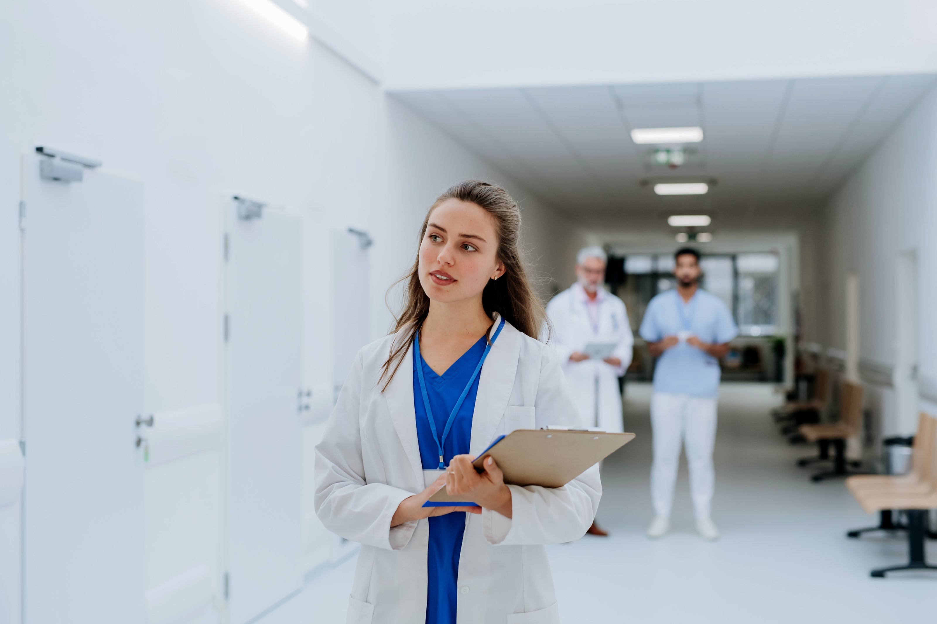 En sykepleier i en sykehuskorridor holder en utklippstavle.