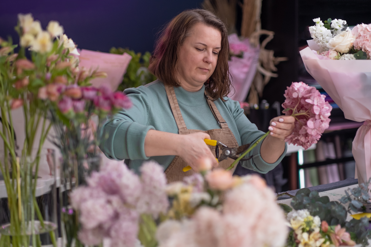 En kvinne klipper blomster i en blomsterbutikk.