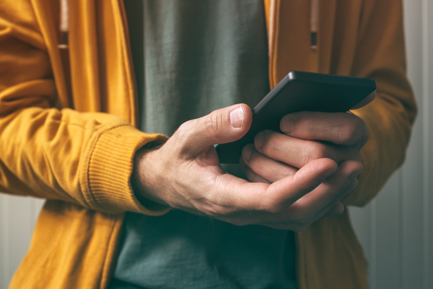 En mann som holder en mobiltelefon i hendene.