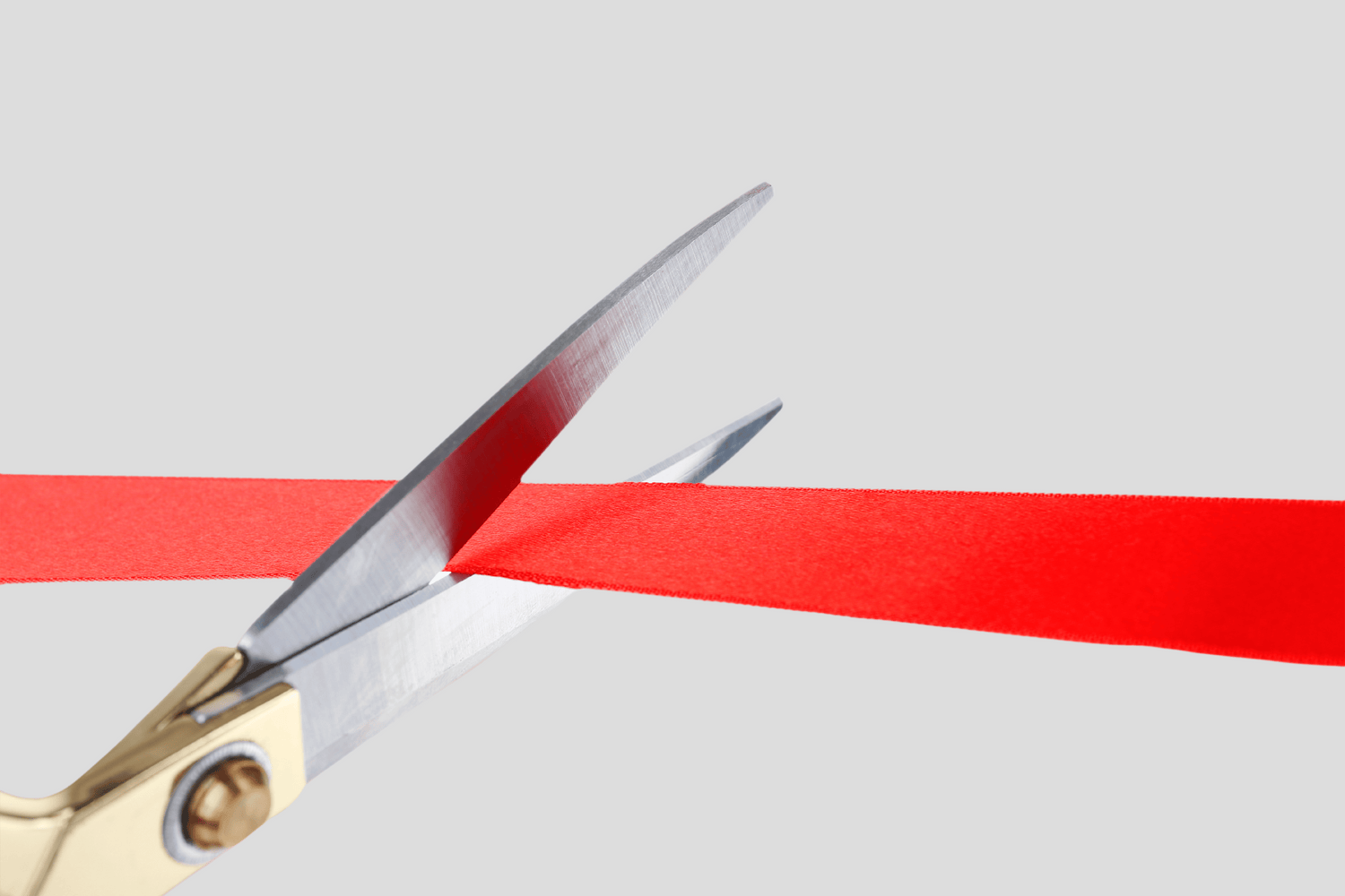 En saks klipper et rødt bånd.