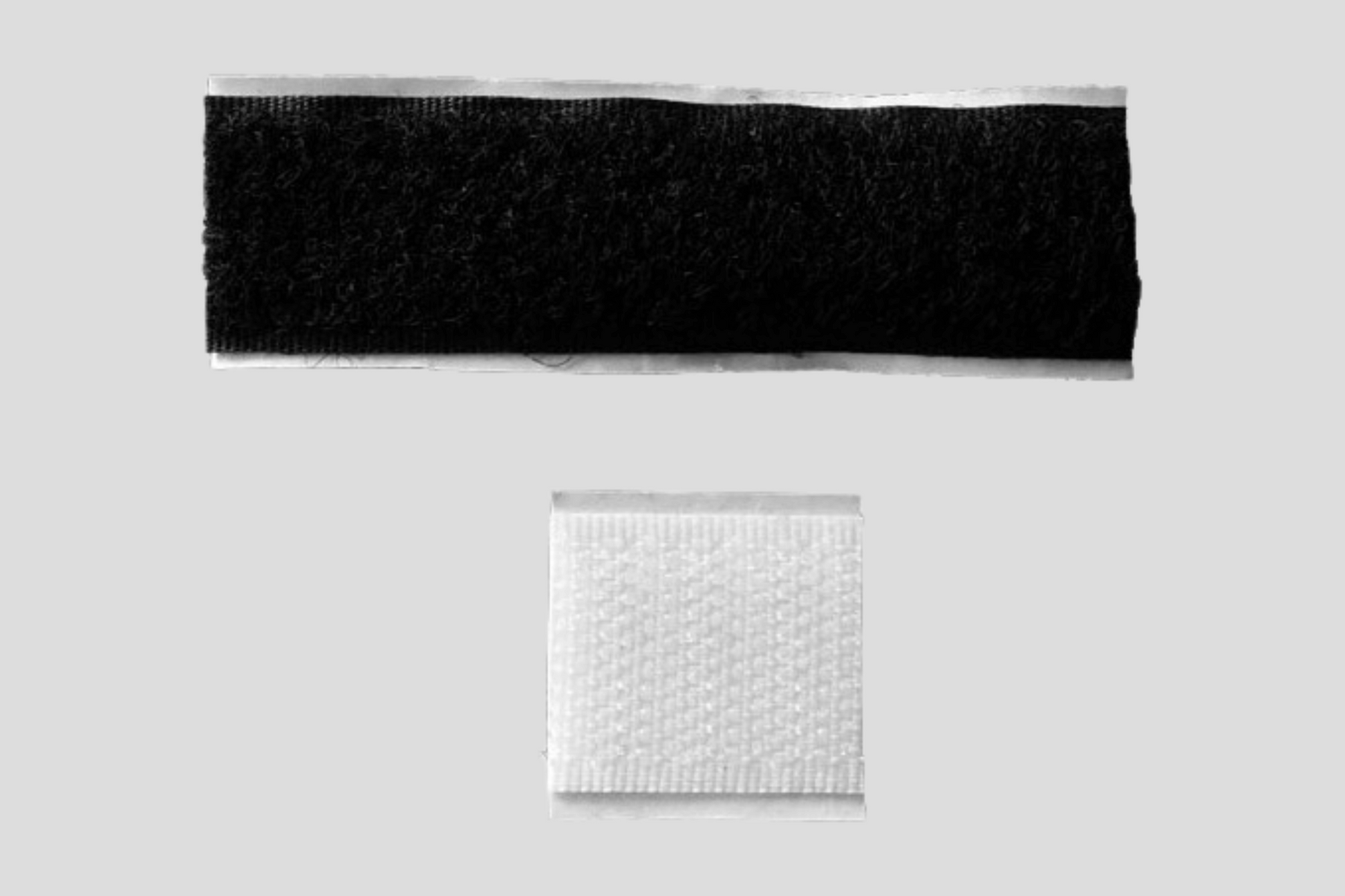 Et sort og hvitt tøystykke med JM Band NOs Selvklebende borrelåslåser.