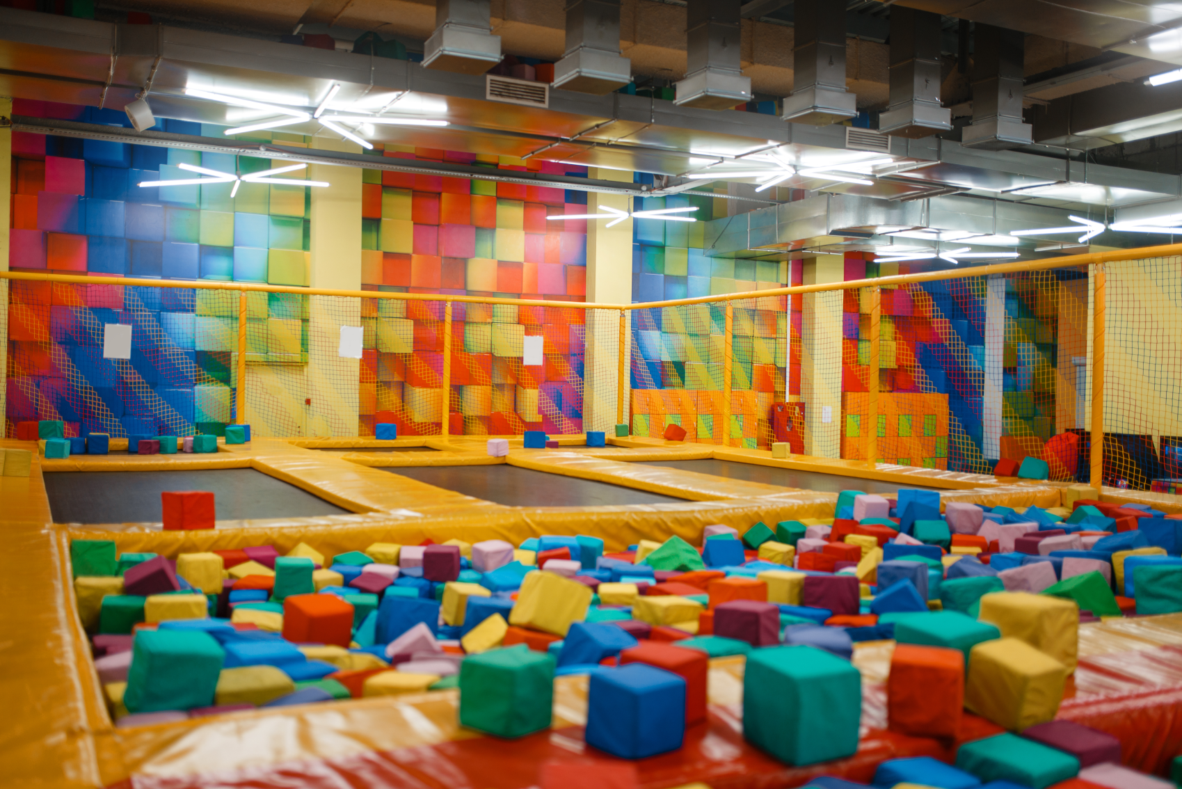 Et innendørs lekeområde med fargerike blokker og en trampoline.