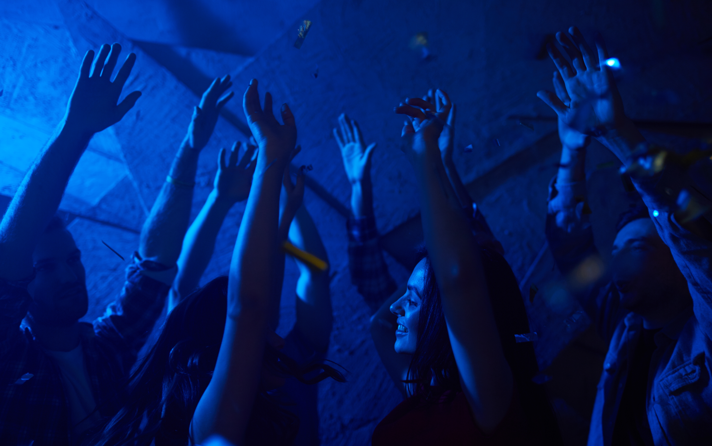 En gruppe mennesker løfter hendene i været på en fest.