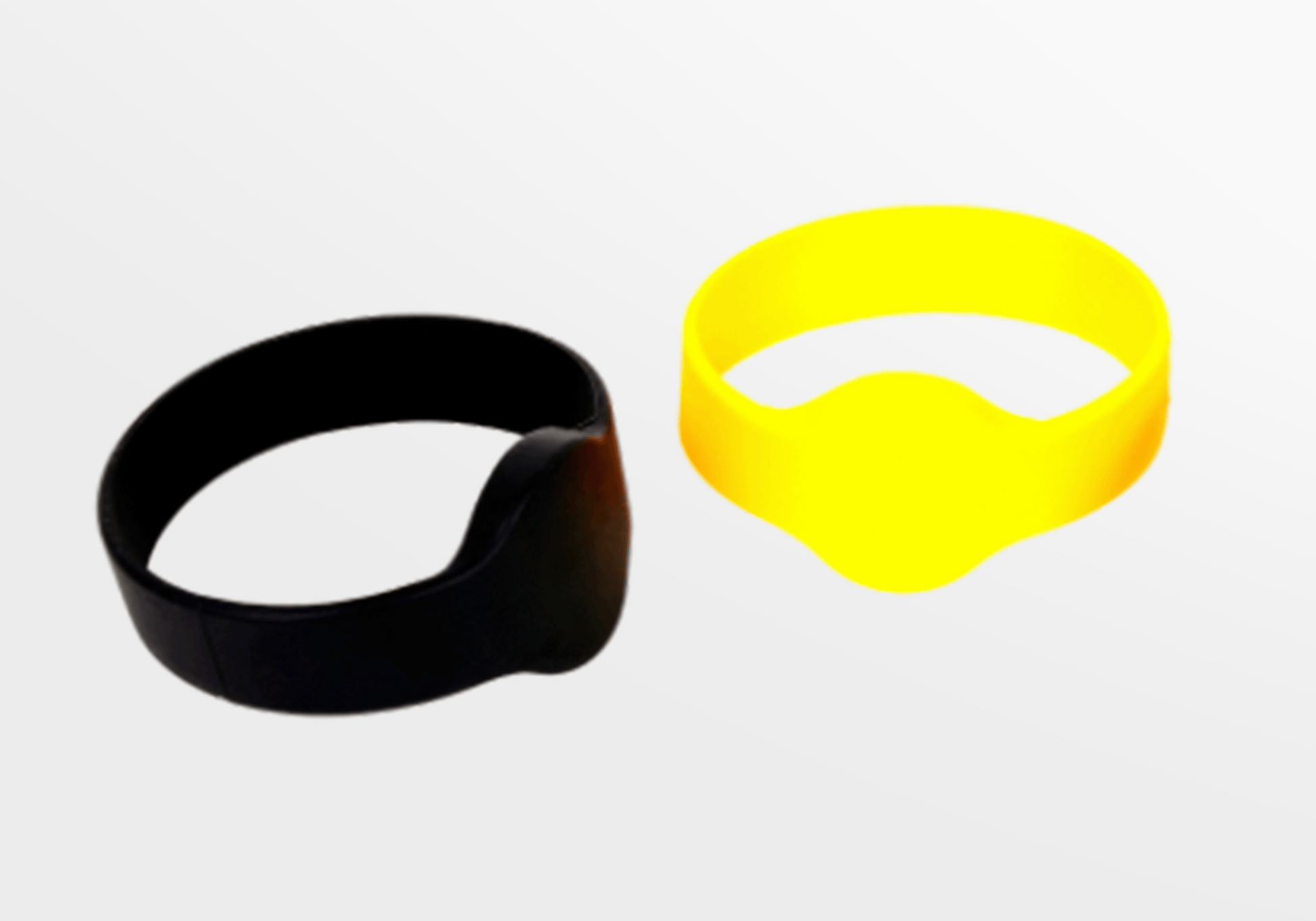 Et par sorte og gule RFID Silikon Armbånd med MiFare Ultralight EV1 gummiarmbånd av JM Band NO på en hvit overflate.