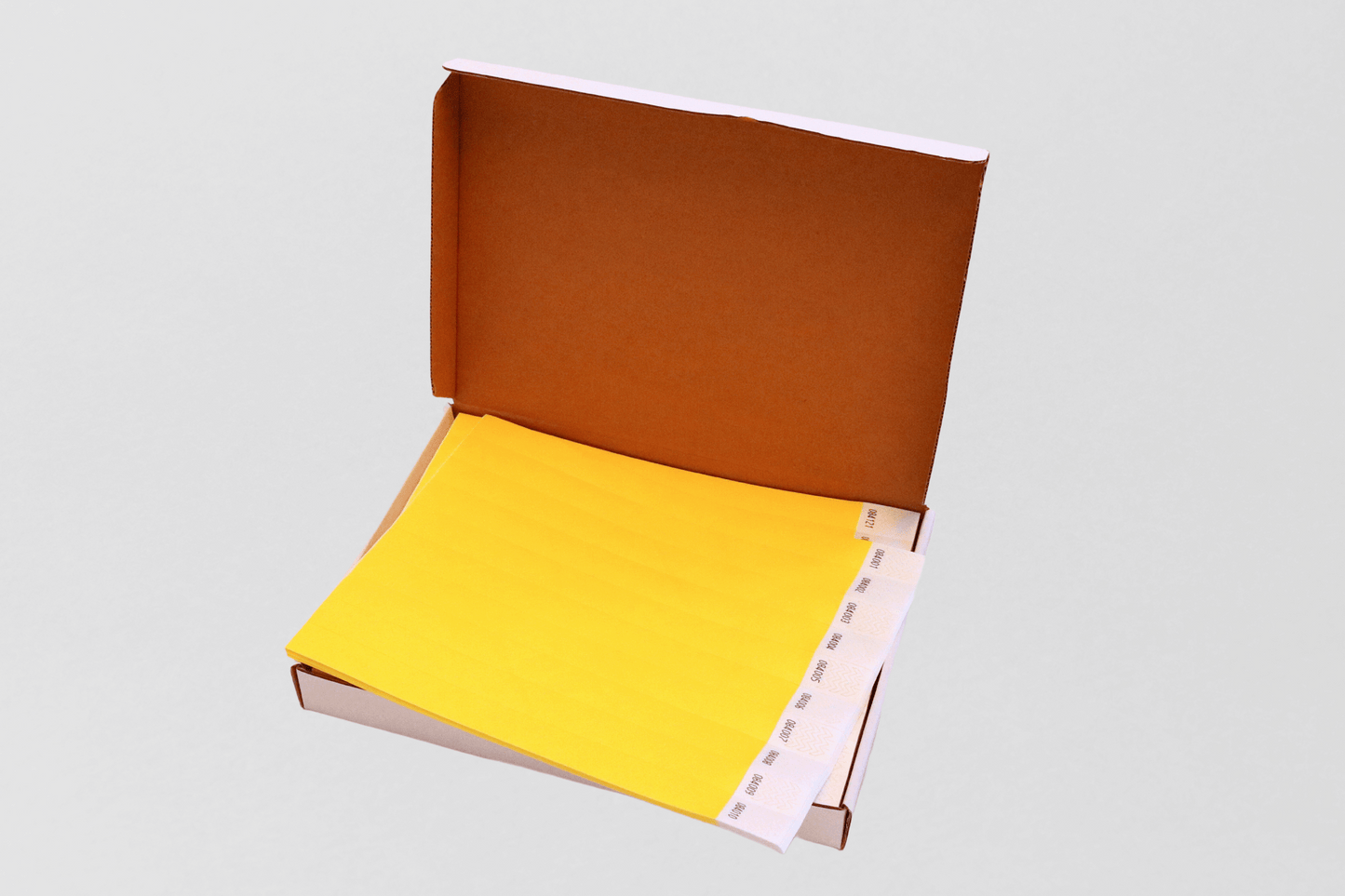 Et gult ark uten trykk i en boks på hvit bakgrunn, Kasse med 1000 papirarmbånd av JM Band NO.